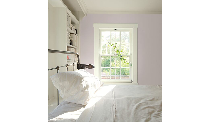 Large bedroom with light pink walls, white built-in shelves, and a metal bedframe with white sheets. Large bedroom with light pink walls, white built-in shelves, and a metal bedframe with white sheets.
