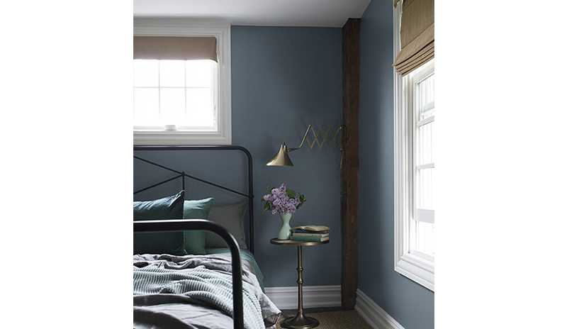 A blue bedroom painted in Black Pepper 2130-40 with exposed wood beams and a black-metal bed frame. A blue bedroom painted in Black Pepper 2130-40 with exposed wood beams and a black-metal bed frame.