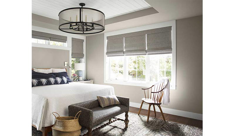 A well-lit, neutral bedroom with large white bed and blue pillows, wooden spindle-back chair. A well-lit, neutral bedroom with large white bed and blue pillows, wooden spindle-back chair.