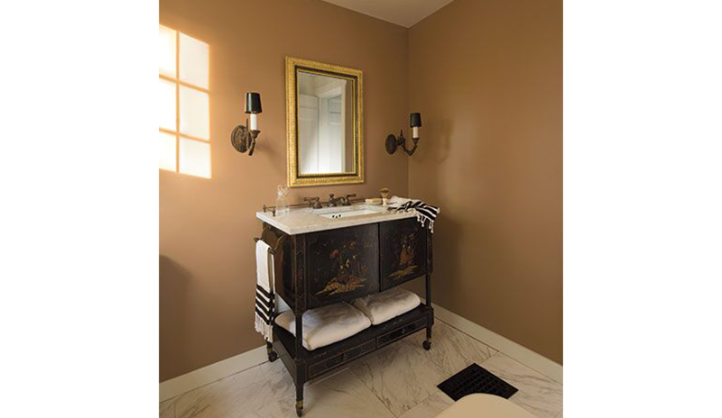 A light orange-painted bathroom with classic sink, gold mirrors, and two wall lights. A light orange-painted bathroom with classic sink, gold mirrors, and two wall lights.