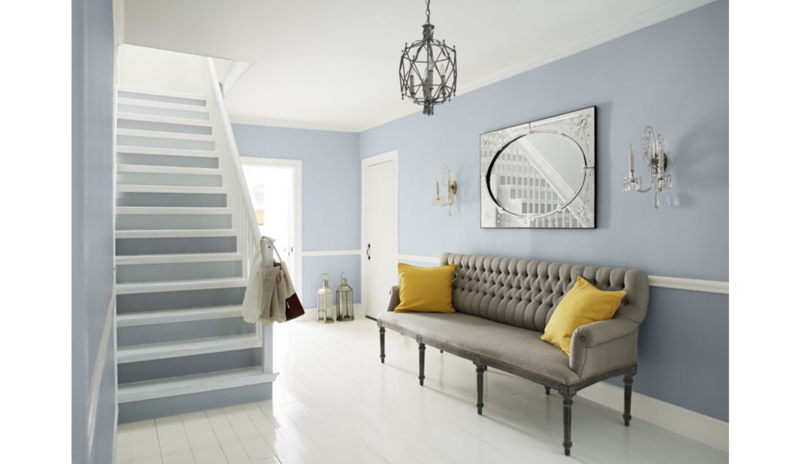 Blue-gray living with two-toned stairs, wainscoting, gray couch, yellow pillows, cage chandelier Blue-gray living with two-toned stairs, wainscoting, gray couch, yellow pillows, cage chandelier