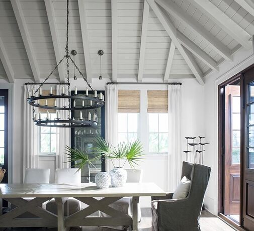 A modern white dinning room with wood-paneled ceiling and hanging candle lit chandelier. A modern white dinning room with wood-paneled ceiling and hanging candle lit chandelier.